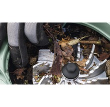 Detail řezacího mechanismu zahradního drtiče se zahradními rukavicemi a listím