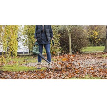 Osoba používá fukar na listí na zahradě k odstranění spadaného listí.