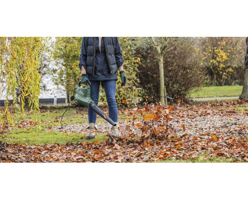 Osoba používá fukar na listí na zahradě k odstranění spadaného listí.