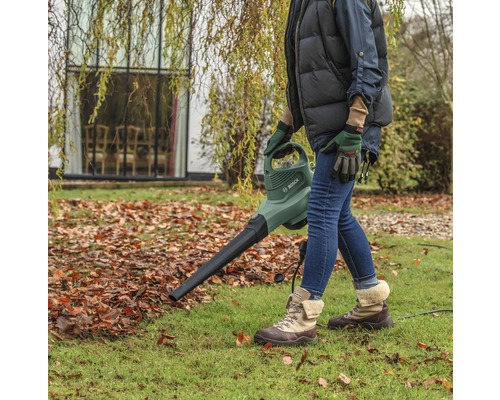 Osoba používá fukar na listí Bosch na zahradě.