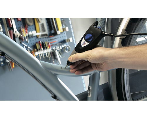 Muž používá gravírovací stroj k vyrytí čísla do rámu jízdního kola.