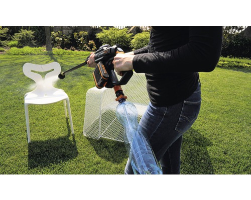 Osoba používá akumulátorovou tlakovou myčku na zahradě k čištění židle. K tlakové myčce je připojena láhev s vodou.