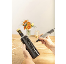 Osoba gravíruje skleněnou láhev iniciálami a datem pomocí gravírovacího nástroje Dremel.