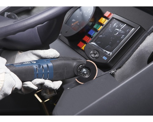 Operátor s ochrannými rukavicemi používá multifunkční nástroj k řezání materiálu na staveništi