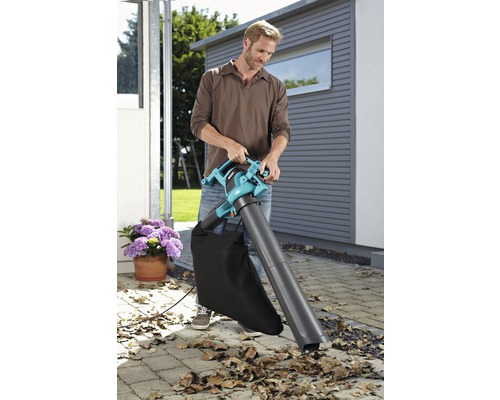 Muž používá vysavač listí na zahradě.