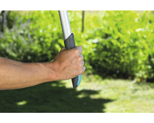 Ruka drží zahradní nářadí s rukojetí v zahradě