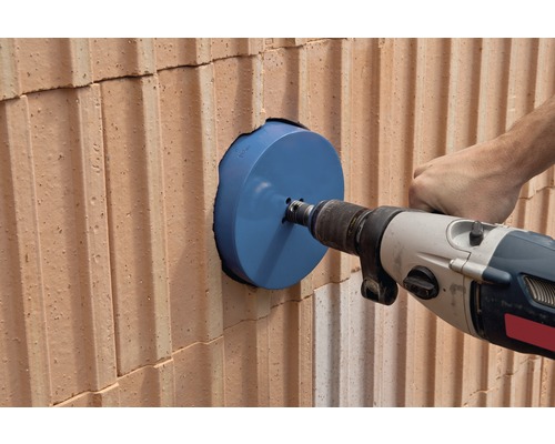 Vrtací stroj vrtá otvor do cihlové zdi pomocí děrovky.