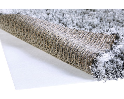 Detailní pohled na šedý chlupatý koberec, srolovaný pro zobrazení textury