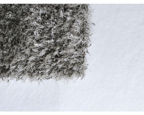 Detailní pohled na šedý koberec s vysokým vlasem.