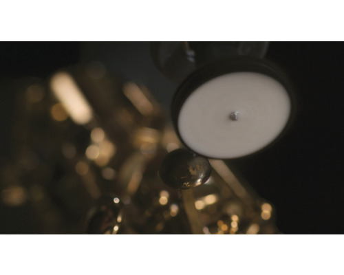 Detailní záběr zlatého saxofonu s bílými polštářky a klapkami