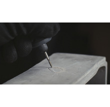 Osoba gravíruje objekt pomocí gravírovacího stroje.