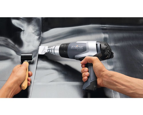 Osoba používá horkovzdušnou pistoli Steinel HG 2320 E a přítlačný váleček pro zpracování střešních krytin.