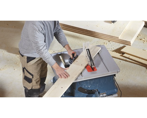 Osoba řeže dřevěnou desku pomocí stolní pily.