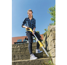 Žena odstraňuje plevel elektrickým odstraňovačem plevele na kamenném schodišti.