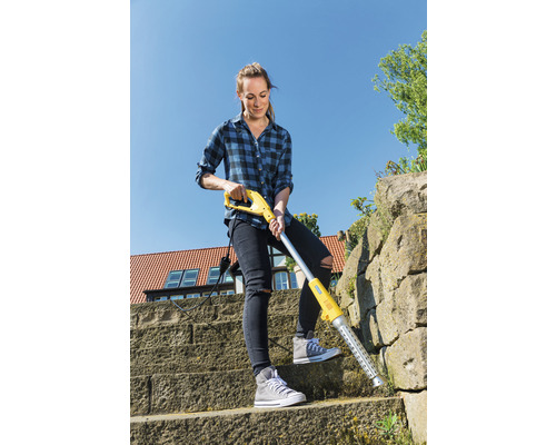 Žena odstraňuje plevel elektrickým odstraňovačem plevele na kamenném schodišti.