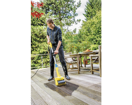 Muž čistí dřevěnou terasu čističem teras.