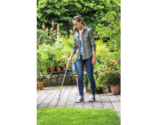 Žena používá plynový hořák k hubení plevele na terase.