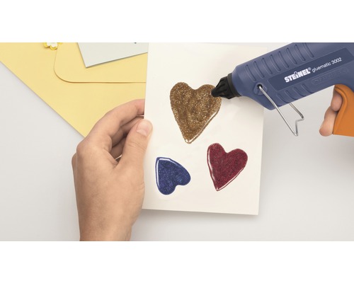 Horkovzdušná pistole nanáší třpytivá srdíčka na papír