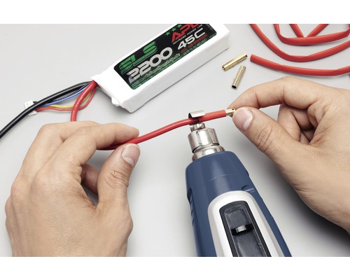 Osoba používá horkovzdušnou pistoli k upevnění konektoru ke kabelu. V pozadí je vidět baterie SLS.