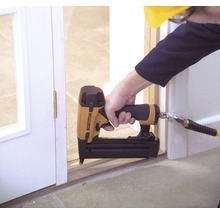 Osoba používá pneumatickou hřebíkovačku Bostitch k připevnění rámu dveří.