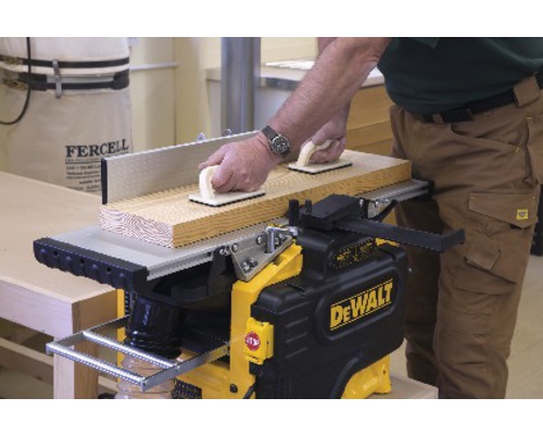 Hoblík s mužem, který vede dřevěnou desku s úchopnými bloky.