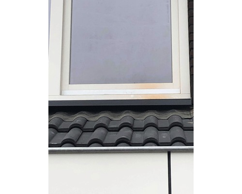 Detailní pohled na střechu s taškami a okno.