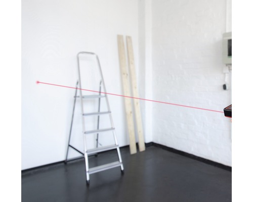 Místnost s žebříkem, dřevěnými deskami a laserovým dálkoměrem s červeným laserovým paprskem