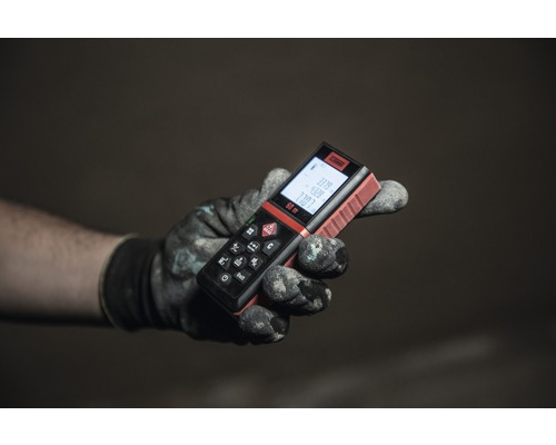 Ruka v pracovní rukavici drží dálkoměr