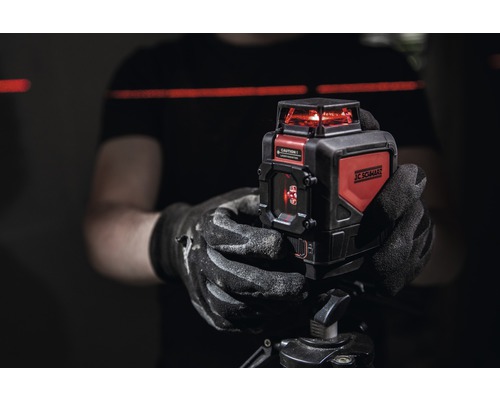 Osoba drží křížový laser JC Schwarz na stativu