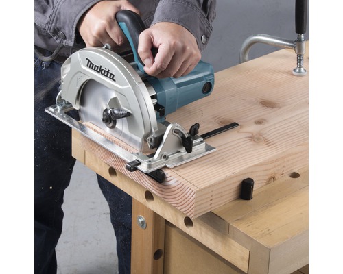 Osoba řeže dřevěnou desku kotoučovou pilou na pracovním stole.