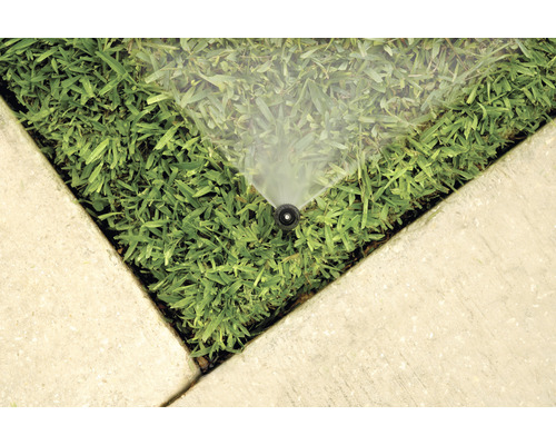 Zavlažovací systém na trávníku blízko betonových desek