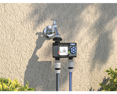 Zavlažovací hodiny na vodovodním kohoutku se dvěma připojenými vodními hadicemi