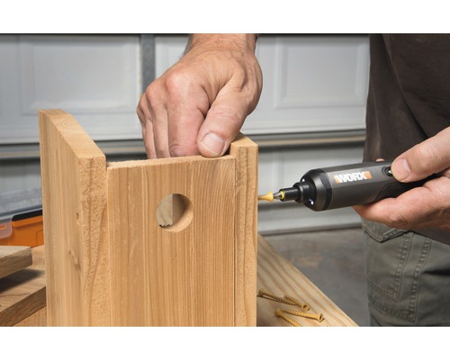 Osoba používá šroubovák k sestavení dřevěné ptačí budky.