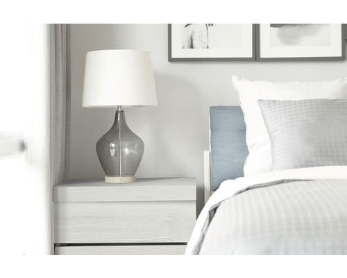 Noční stolek s lampou a postelí v ložnici