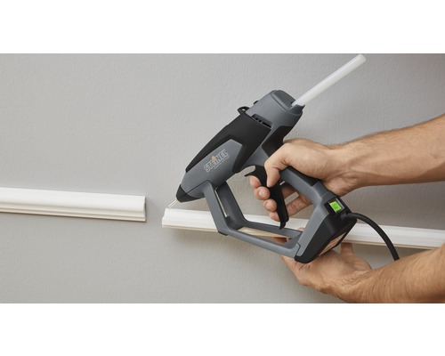 Osoba používá tavnou pistoli Steinel k připevnění ozdobné lišty na zeď.