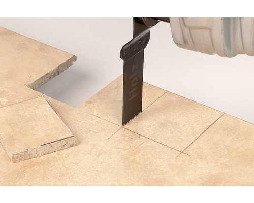 Oscilační pila řeže dlaždici podél čáry tužky.