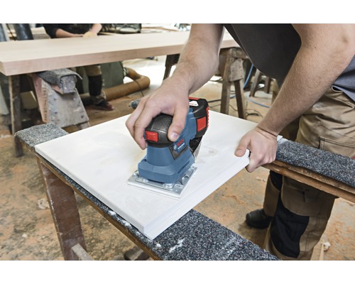 Osoba brousí obrobek elektrickou bruskou.