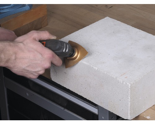 Osoba řeže betonový kámen multifunkčním nástrojem.