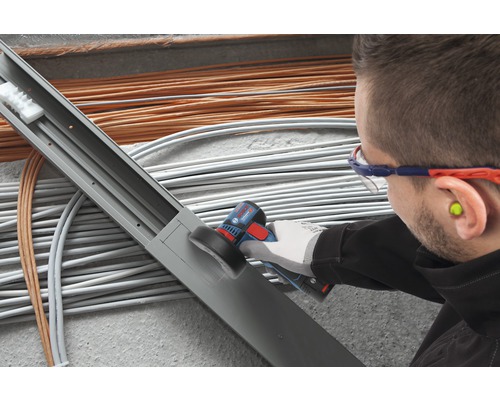 Elektrikář opracovává kabelový kanál multifunkčním nástrojem před kabely