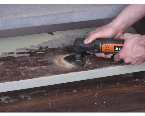 Osoba používá multifunkční nástroj k broušení dřevěného povrchu. Logo AEG.