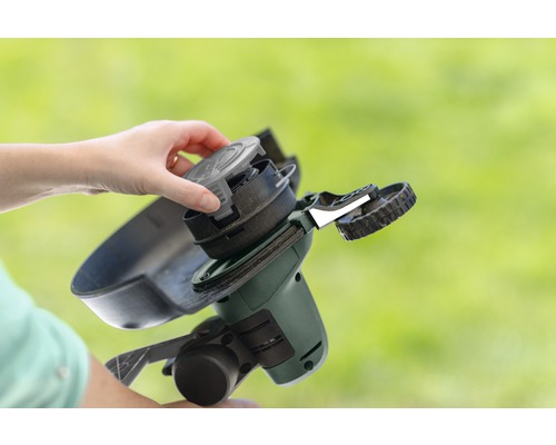 Osoba vyměňuje cívku strunové sekačky.