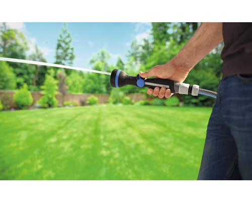 Osoba zalévá zahradu pomocí zahradní stříkací pistole.