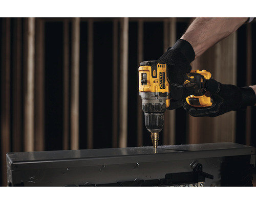 Logo společnosti DeWalt. Osoba vrtá vrtačkou otvor do kovového pouzdra.