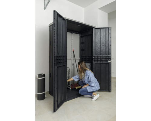 Otevřená plastová skříň na nářadí s uloženými věcmi a osobou před ní.