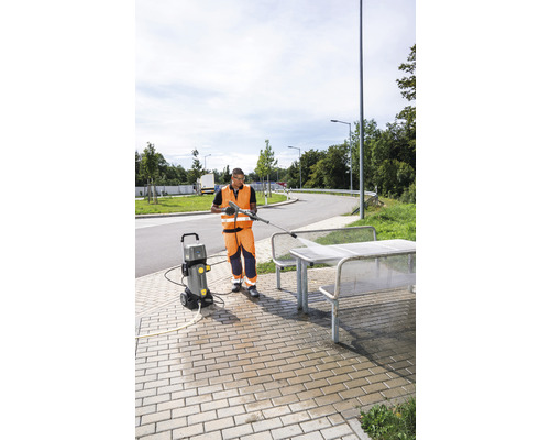 Osoba používá vysokotlaký čistič k čištění venkovního posezení.