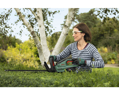 Žena stříhá živý plot pomocí akumulátorových nůžek na živý plot Bosch