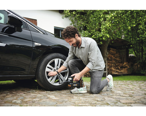 Muž plní pneumatiku auta pomocí hustilky pneumatik Worx.