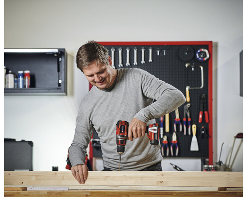 Muž pracuje s akumulátorovým šroubovákem na dřevě v dílně