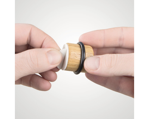 Dřevěná zátka na víno s gumovým těsněním je držena v rukou