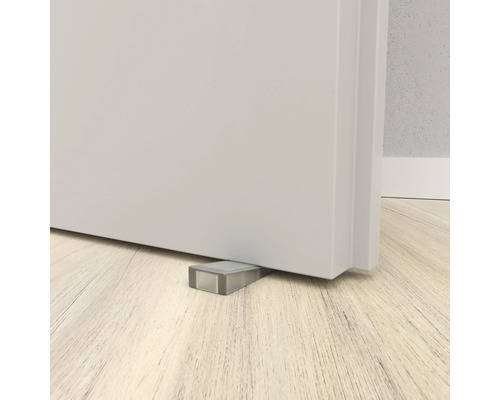 Dveřní zarážka pod dveřmi na dřevěné podlaze